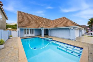 Gated front yard of home with a pebble tech pool.