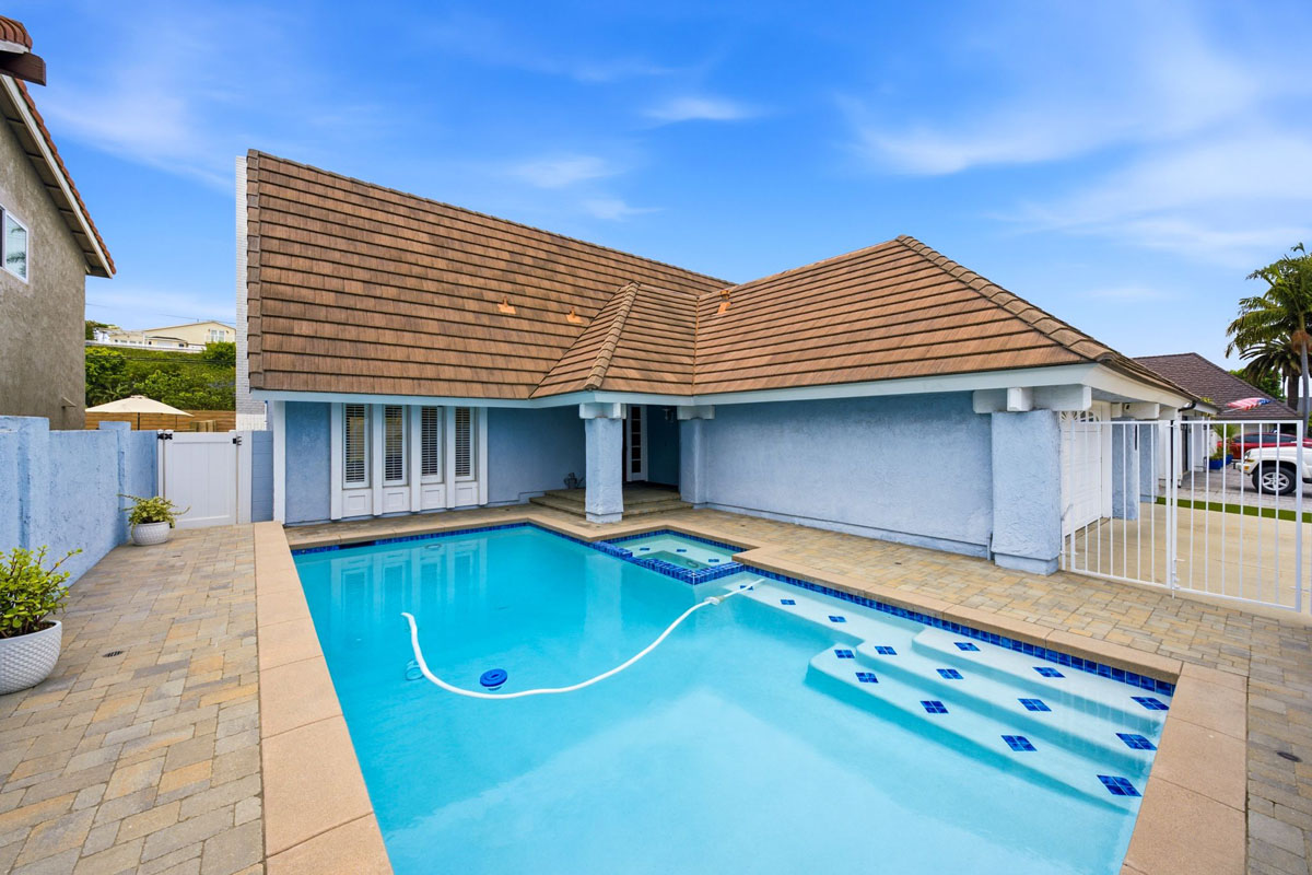 Gated front yard of home with a pebble tech pool.