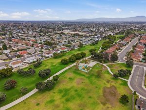 Aerial view of Huntington Beach neighborhood showing homes, streets, side walks and a large greenbelt.