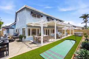 Backyard with a putting green and view of home with attached pergola.