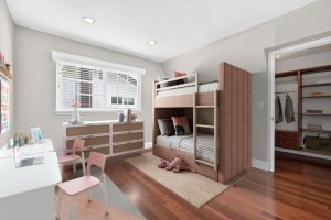 Digitally staged kids room with bunk beds, neutral colored walls and a bright window.