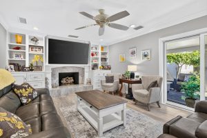 Family room with large mounted tv, a couch and table and built-in shelves around the tv and fireplace.