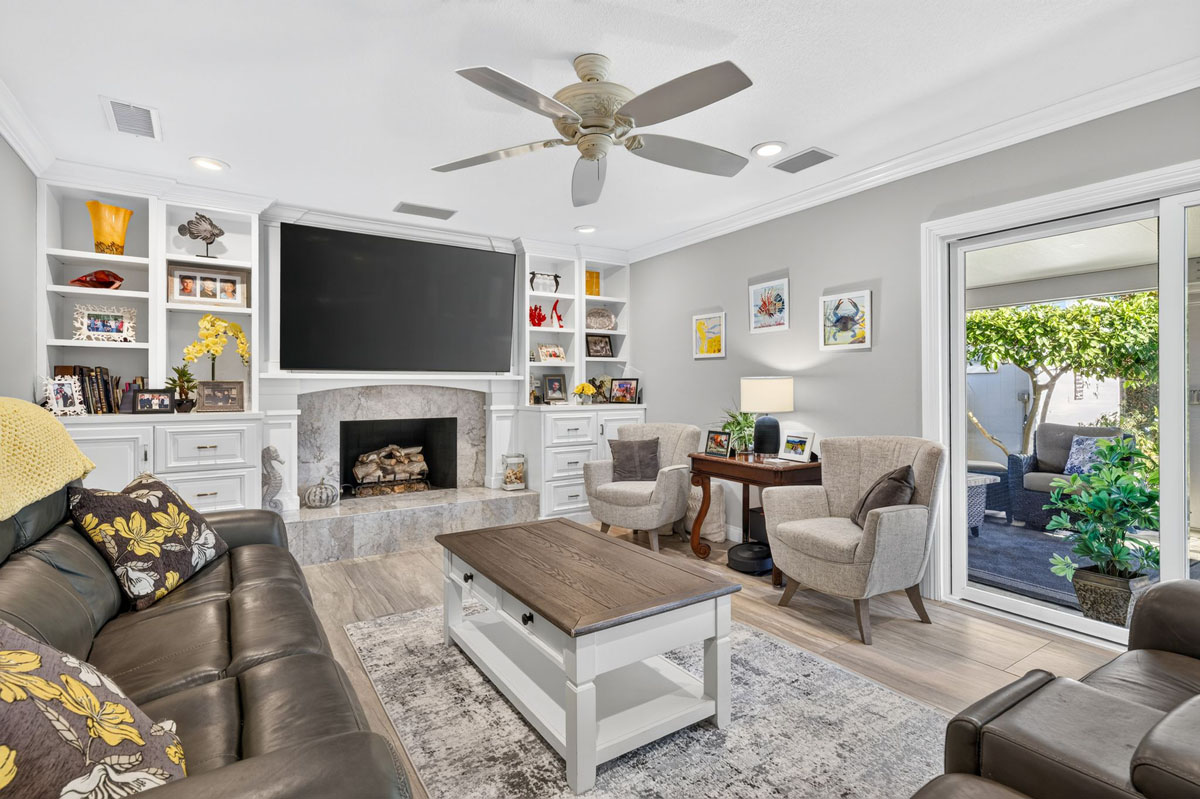 Family room with large mounted tv, a couch and table and built-in shelves around the tv and fireplace.