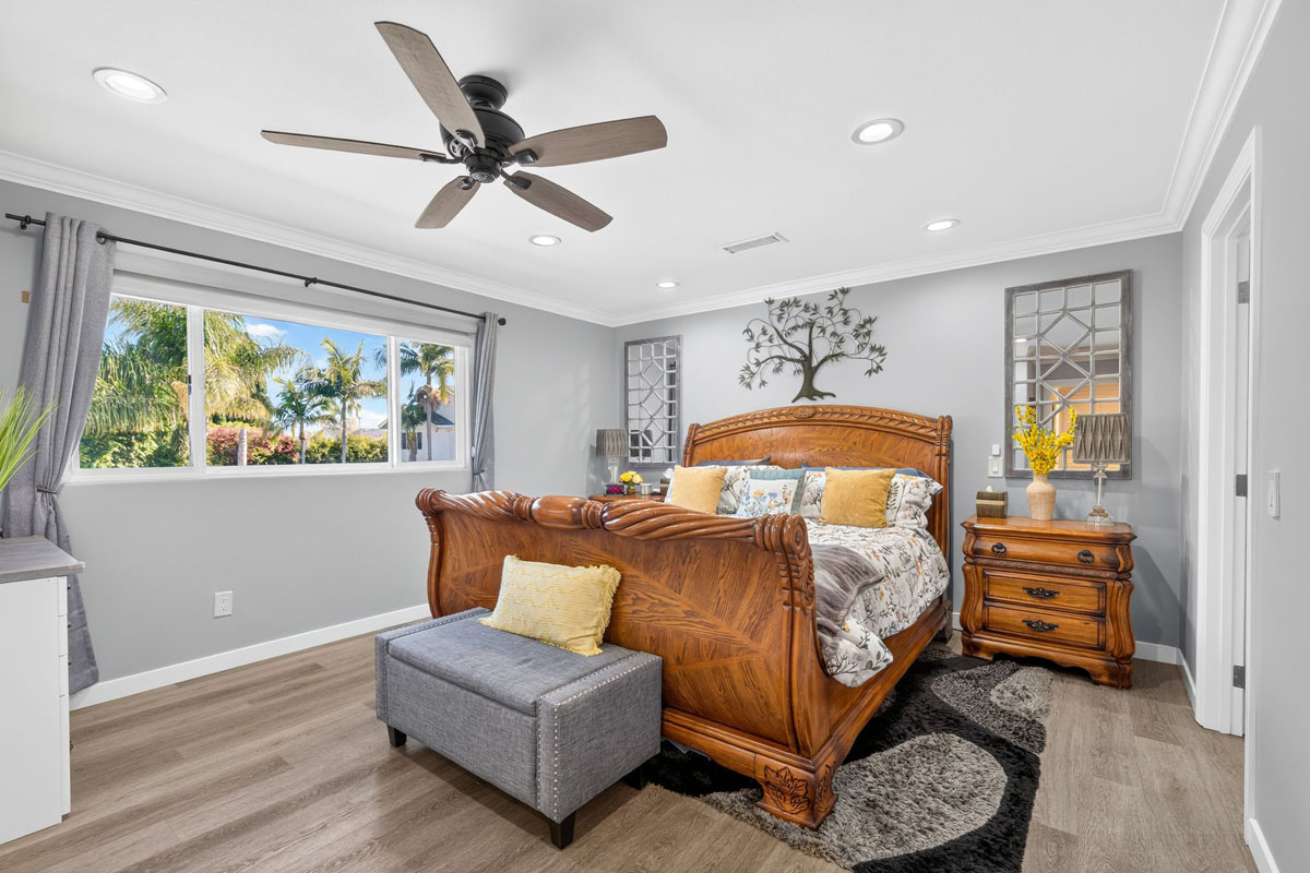 Master bedroom with large bed, ceiling fan and window.