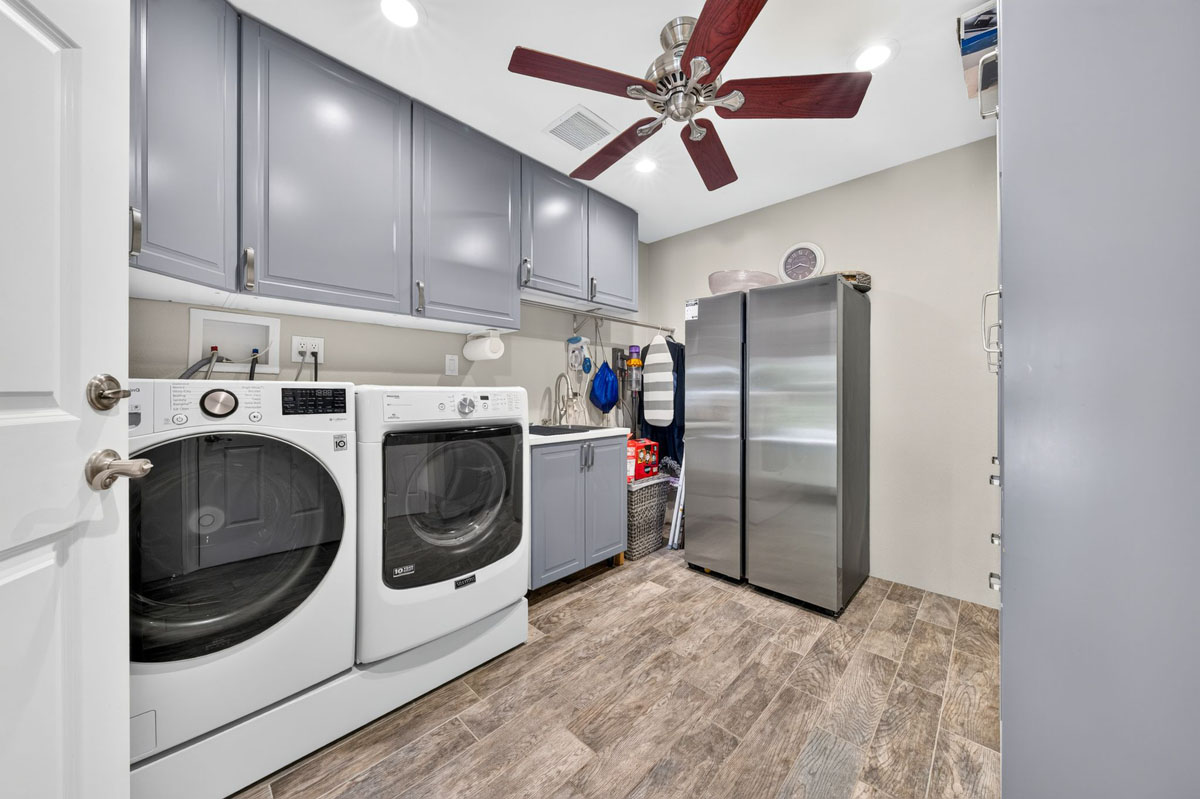 Laundry room with gray cabinetry and a ceiling fan.