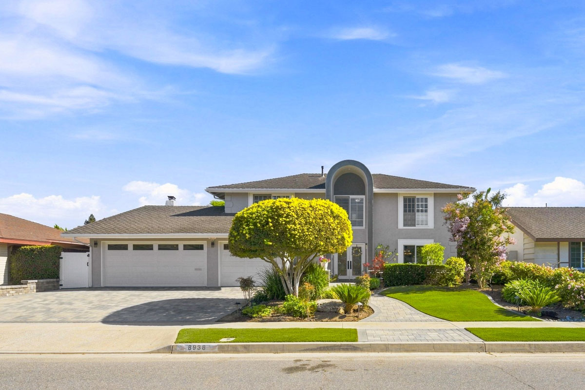 View of 8938 Martin Avenue, Fountain Valley from the street showing neutral paint, white garage doors, and a large tree.