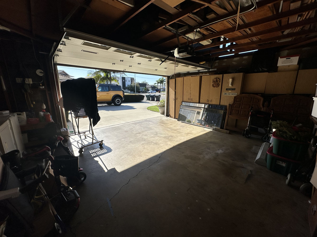 Original garage space with stained concrete and a wall of cabinets in the back.