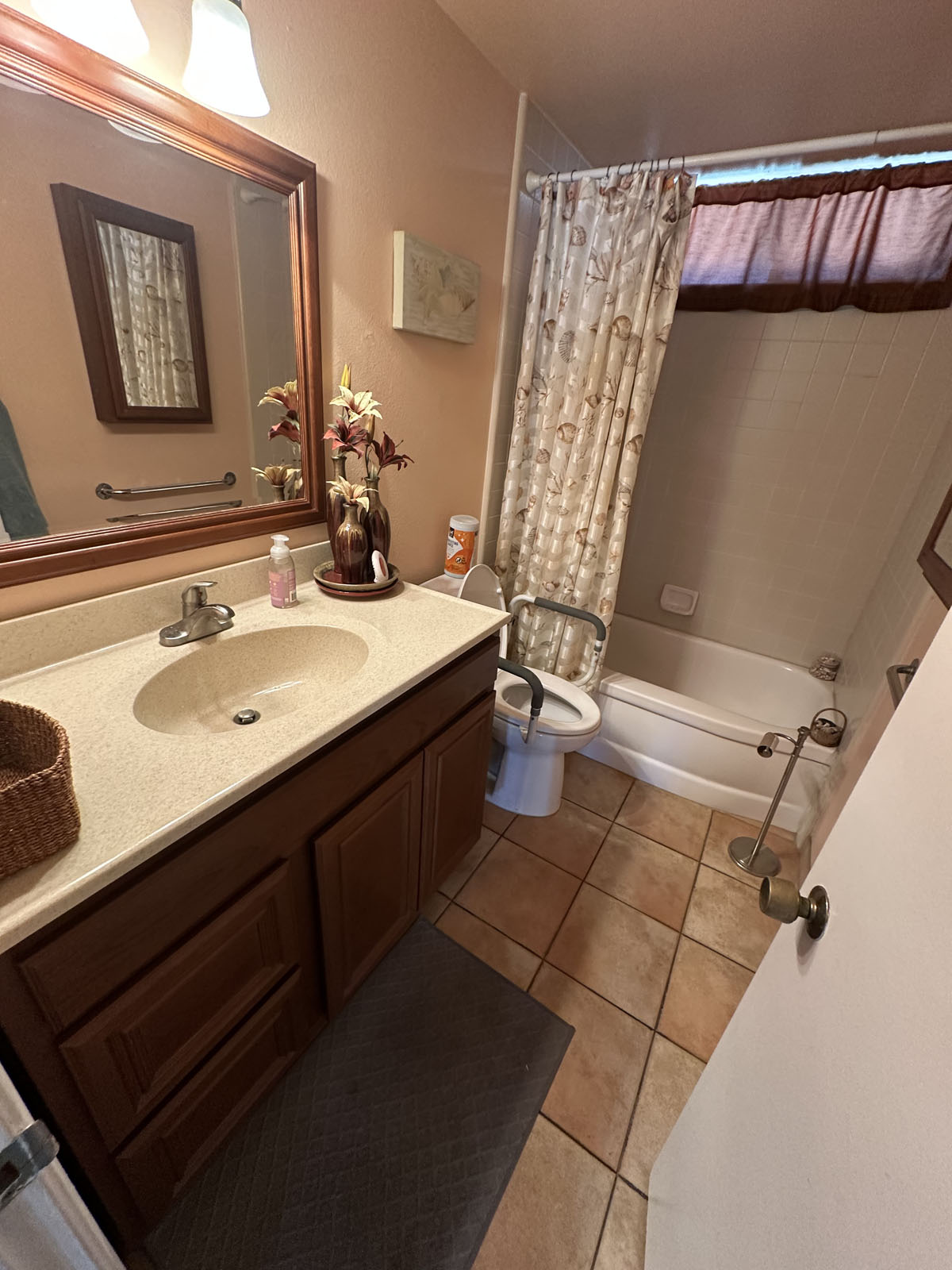 Outdated, dark bathroom with single sink vanity and wood-toned cabinets.
