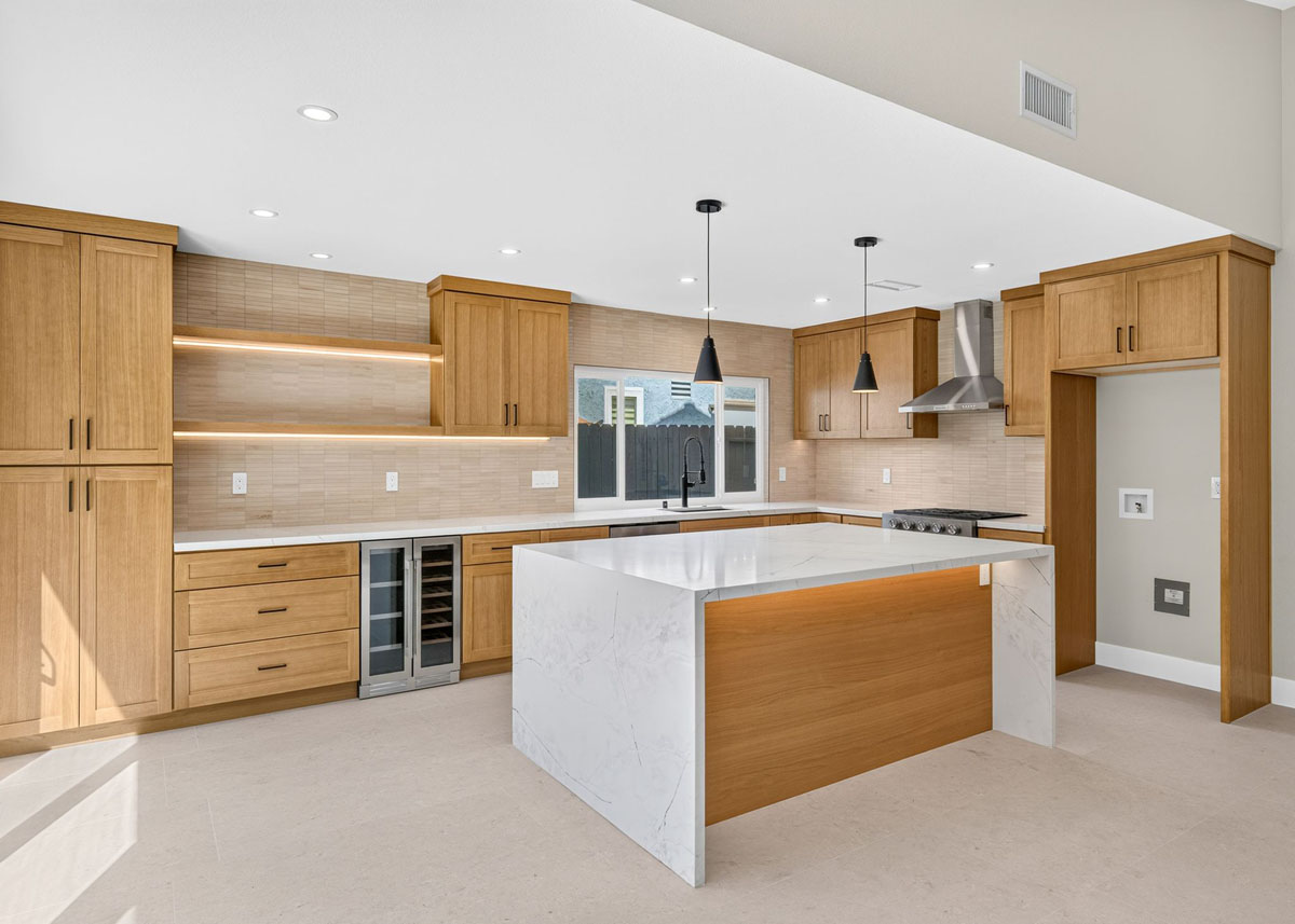 Updated kitchen with medium-toned wood cabinetry, white counter tops and a large island.