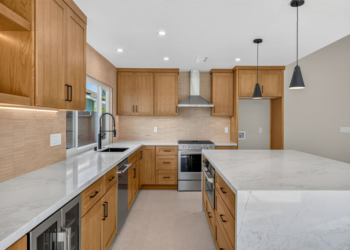 Updated kitchen with medium-toned wood cabinetry, white counter tops and a large island.