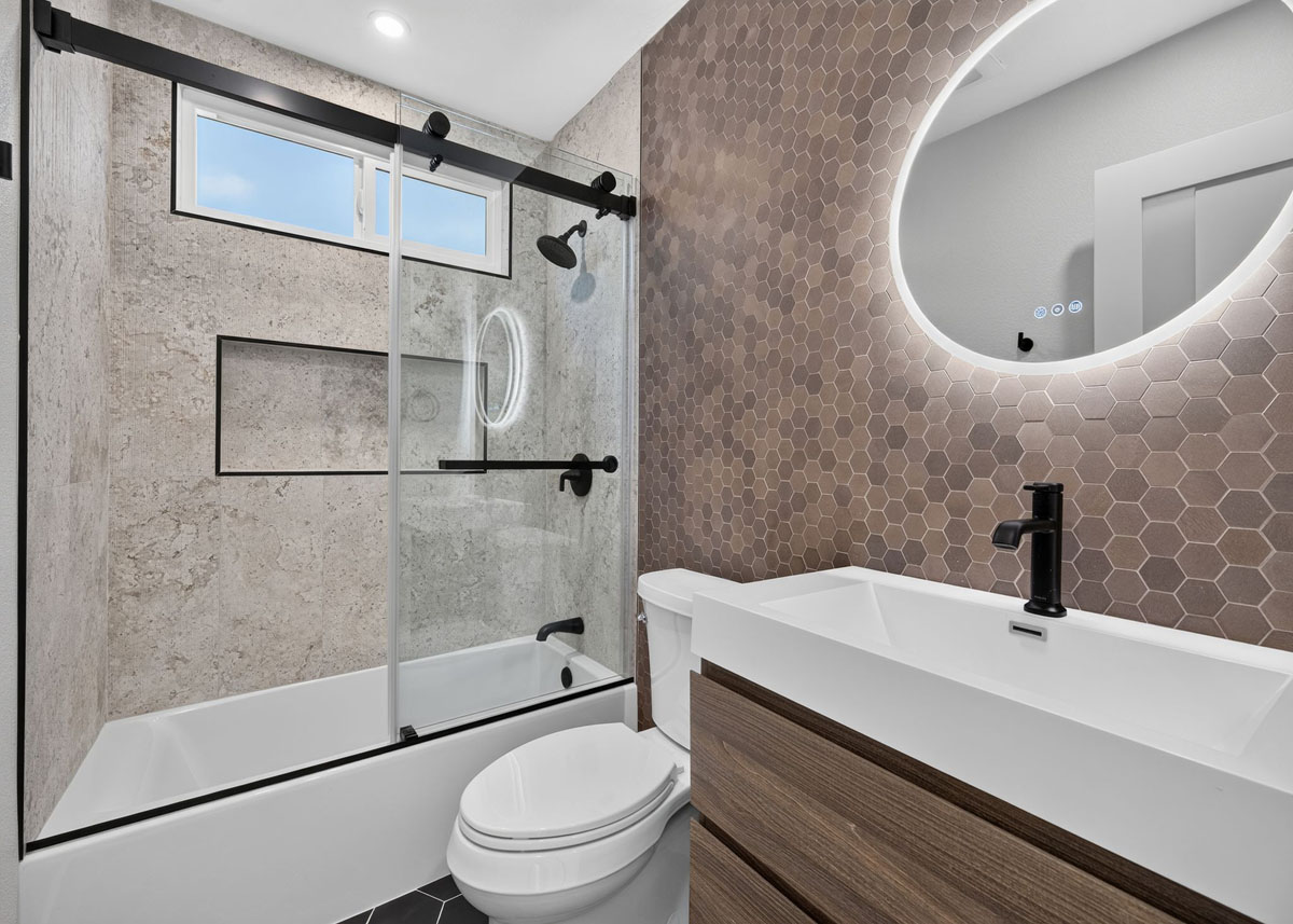 Updated hall bathroom with back-lit circular mirror.