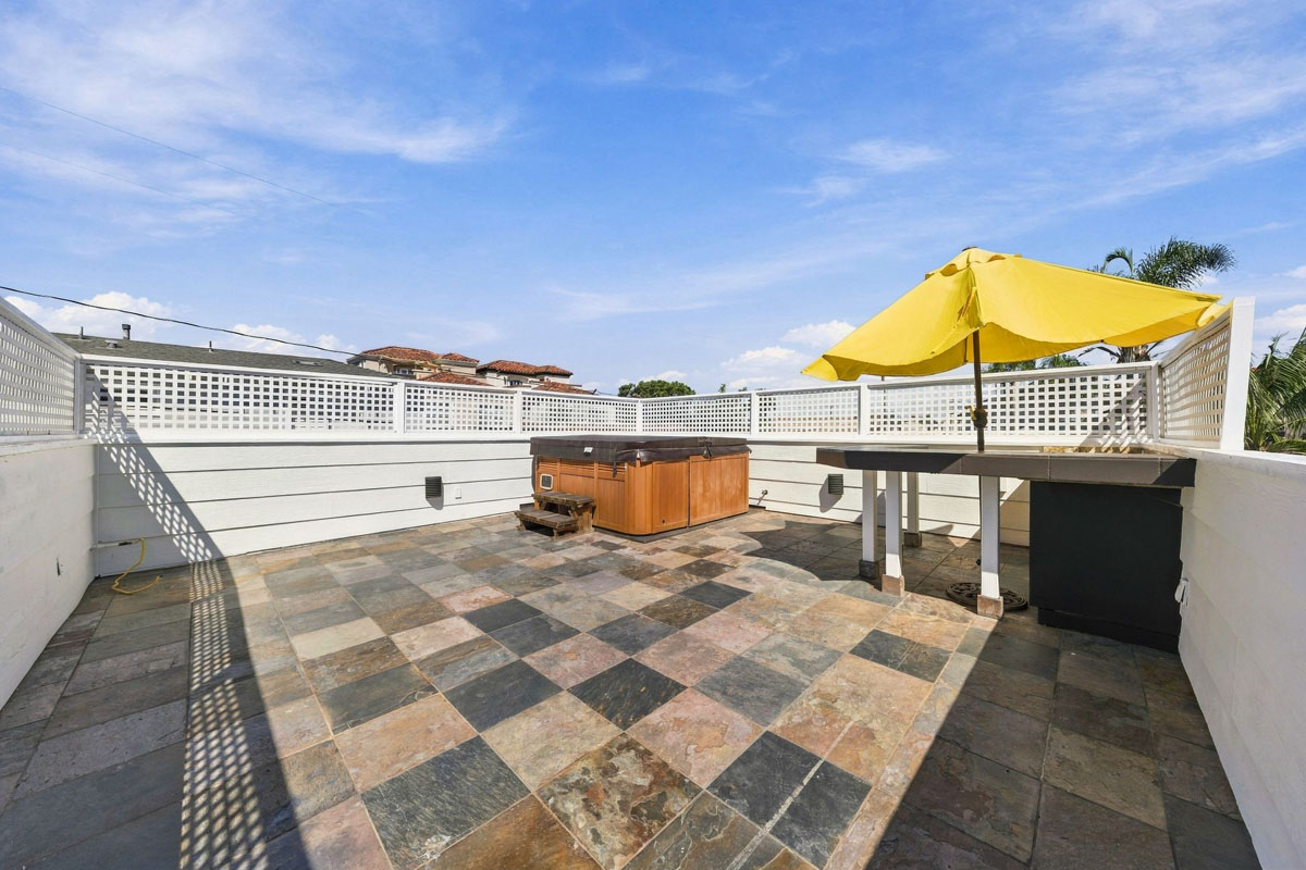 Roof top bar with yellow umbrella and a spa.