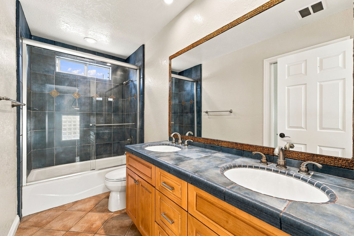 A full bathroom with two sinks, a toilet, and a walk-in shower/tub combo.
