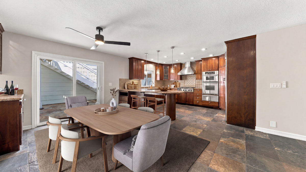 Digitally staged dining space off the kitchen with ceiling fan above table and chairs.